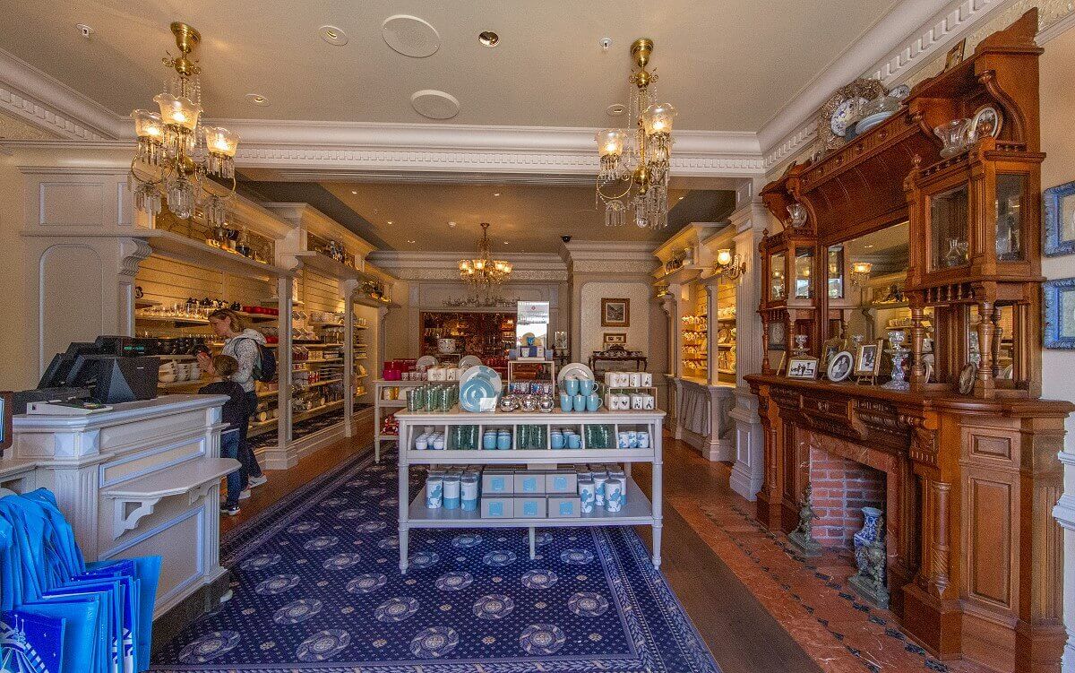 Large salesroom in Lilly's Boutique Large salesroom in Lilly's Boutique: You can see mainly white furniture, on the right there is a large fireplace surrounded by a brown wooden shelf on which numerous pictures and other decorative elements are placed.