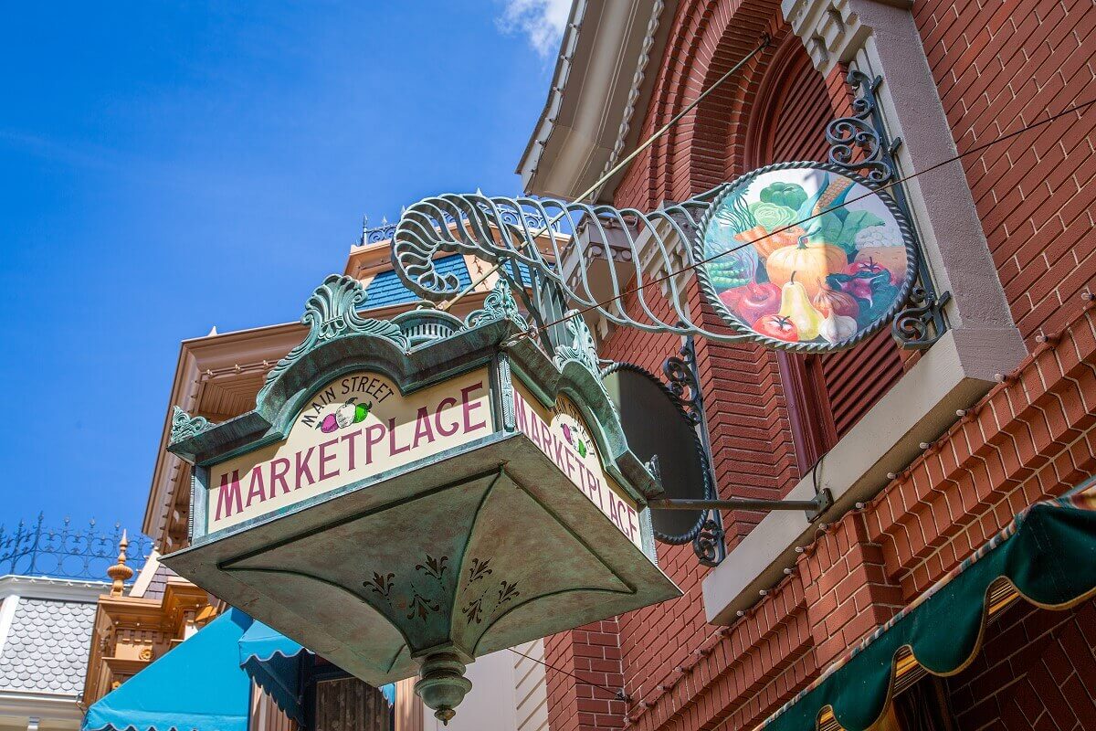 Main Street Marketplace Sign Main Street Marketplace sign hanging above the Marketplace. The green wrought iron sign is decorated with a motif of fresh fruits and vegetables