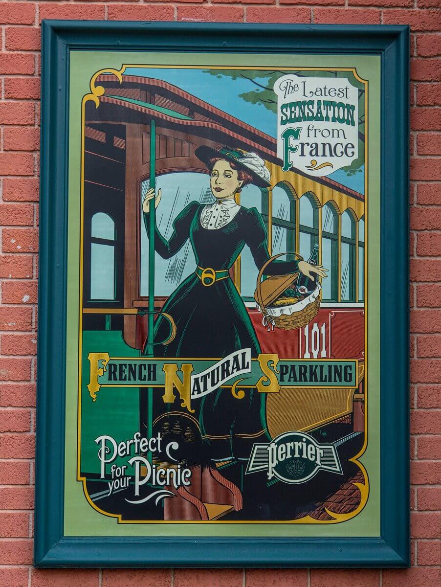 Antique Perrier advertising sign Antique Perrier advertising sign with a woman getting off the Disneyland Railroad