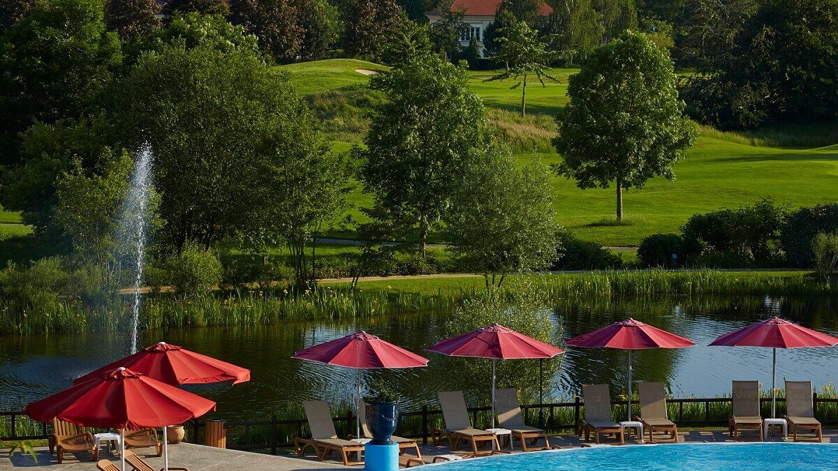 Hotel pool and golf course View from the Marriott Village Hotel to the pool with deck chairs and red sunshades, behind it a lake and the golf course