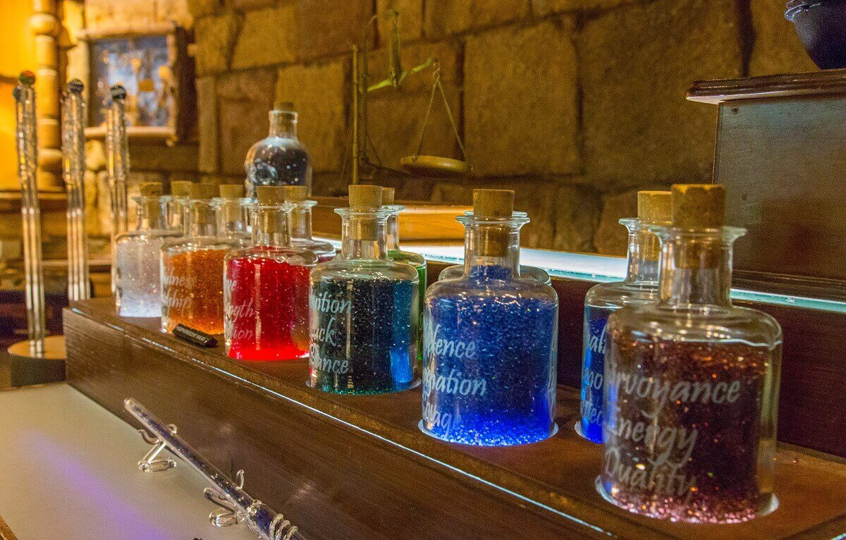 Flask with glass stones On a wooden beam are several vials with different colored small glass stones