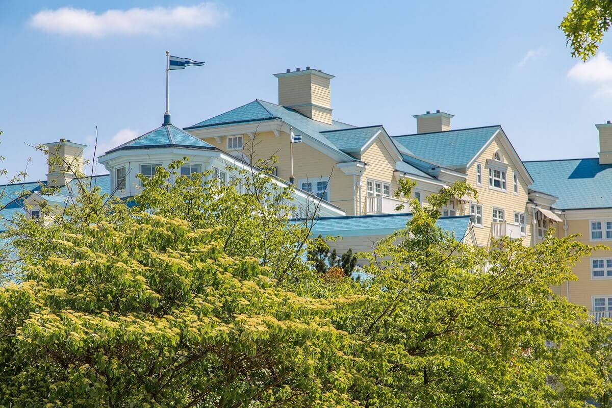 Hotel Newport Bay Club The blue and yellow facade of the Hotel Newport Bay Club is hidden by trees.