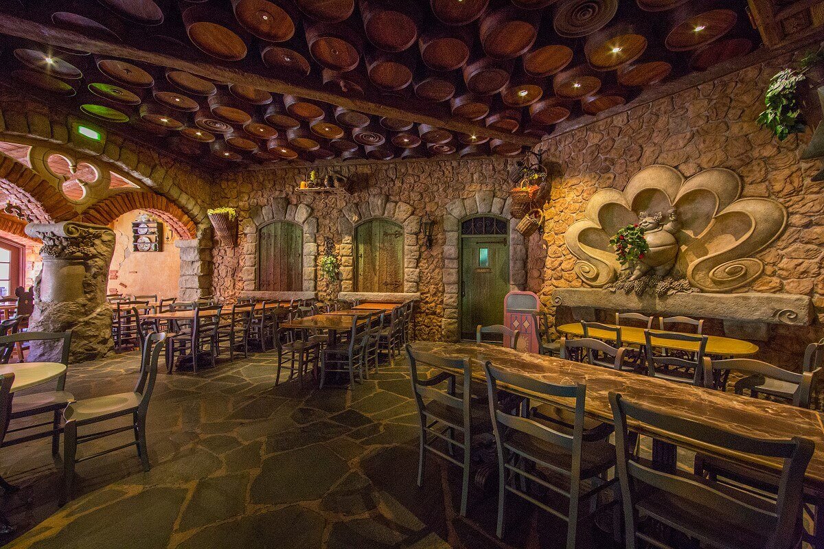 Seating area In one part of the fast food restaurant there are several wooden tables and chairs under a sky of wine barrels