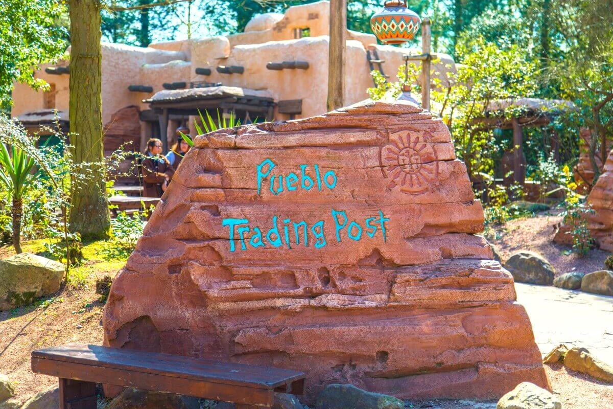 Pueblo Trading Post sign On a red stone is written Pueblo Trading Post in turquoise font