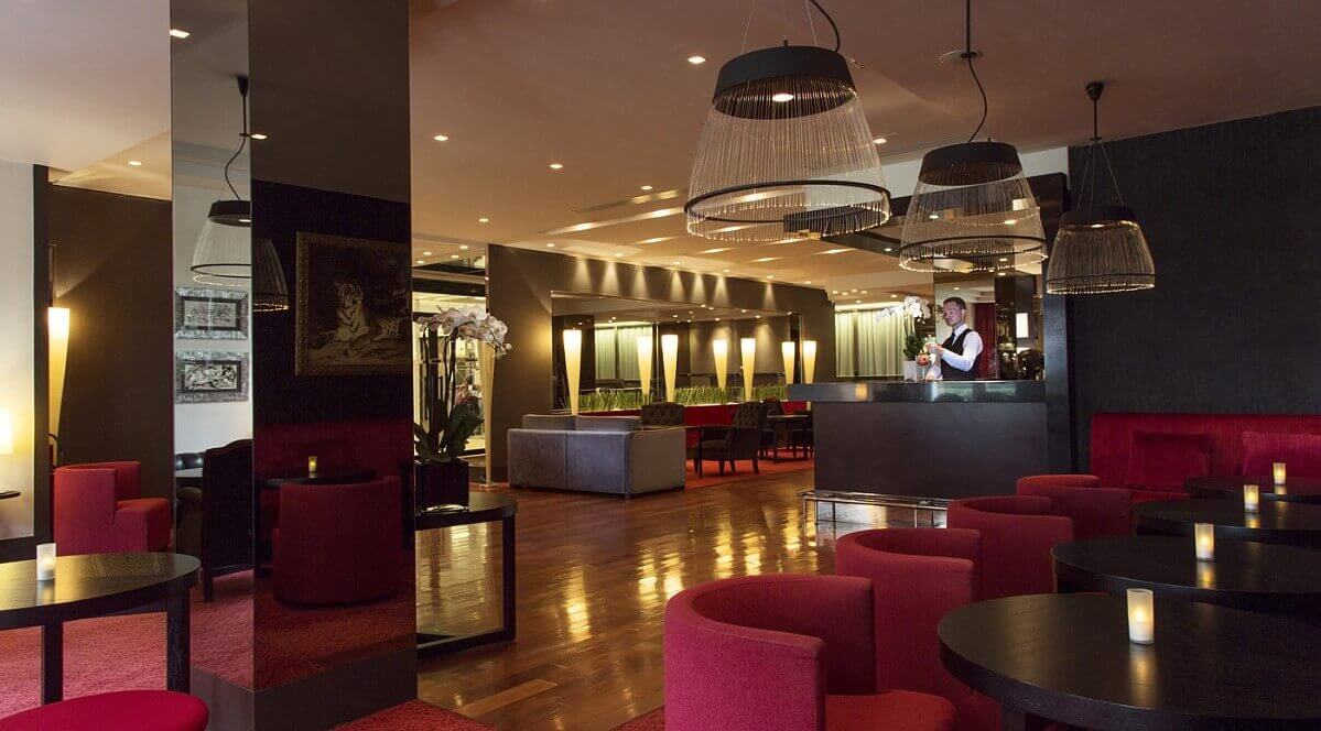 Hotel bar Hotel bar in the Relais Spa with red armchairs, dark brown wooden tables and modern chandeliers