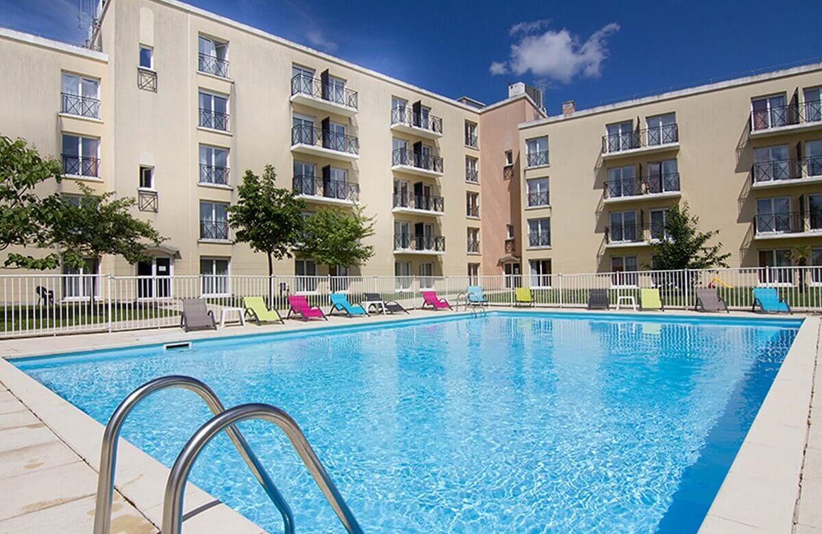 Pool View of the pool in the inner courtyard of the hotel, colorful deck chairs are set up around it
