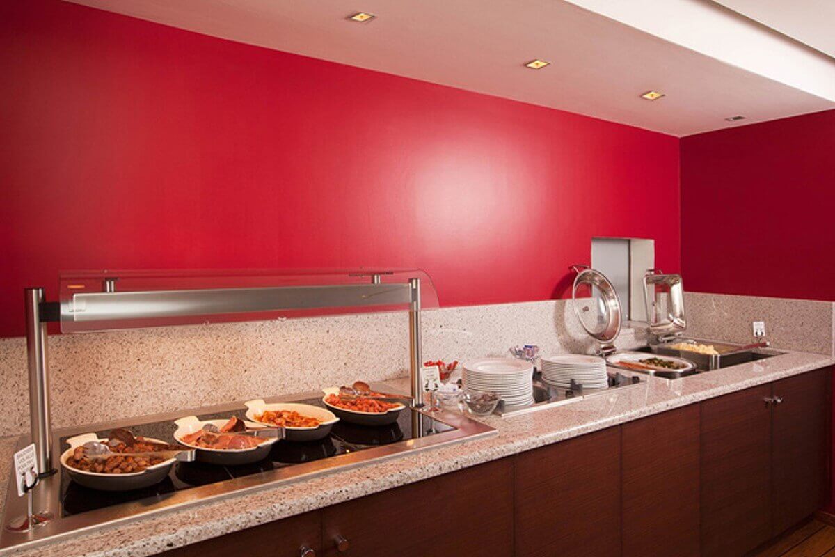 Breakfast View of the breakfast buffet: hot dishes and plates on a sideboard in front of a red wall