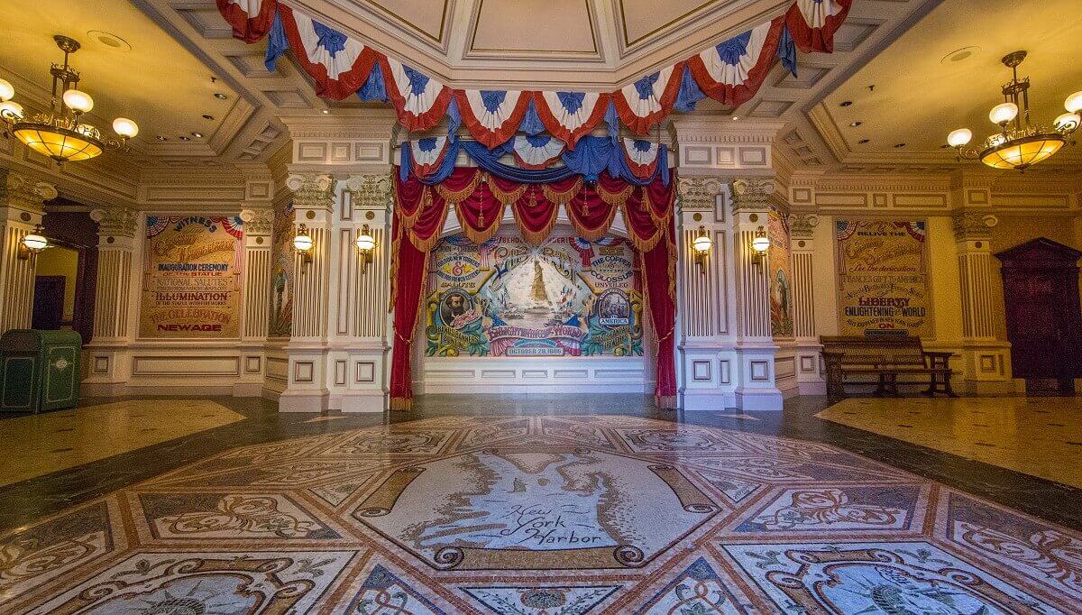 Entrance of the Statue of Liberty Tableau Entrance of the Statue of Liberty Tableau. The entrance is framed by white and gold columns. To the right and left of it are panels with information and drawings about the Statue of Liberty, and behind the portal, which is draped in red velvet, is a historical advertising panel