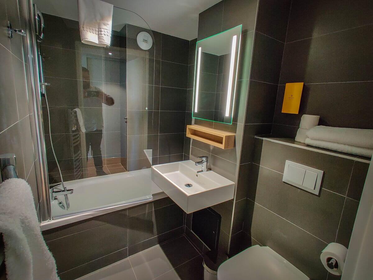 Bad Detailed view from the hotel bathroom with washbasin, mirror, small shelf, WC, waste bin and shower tray