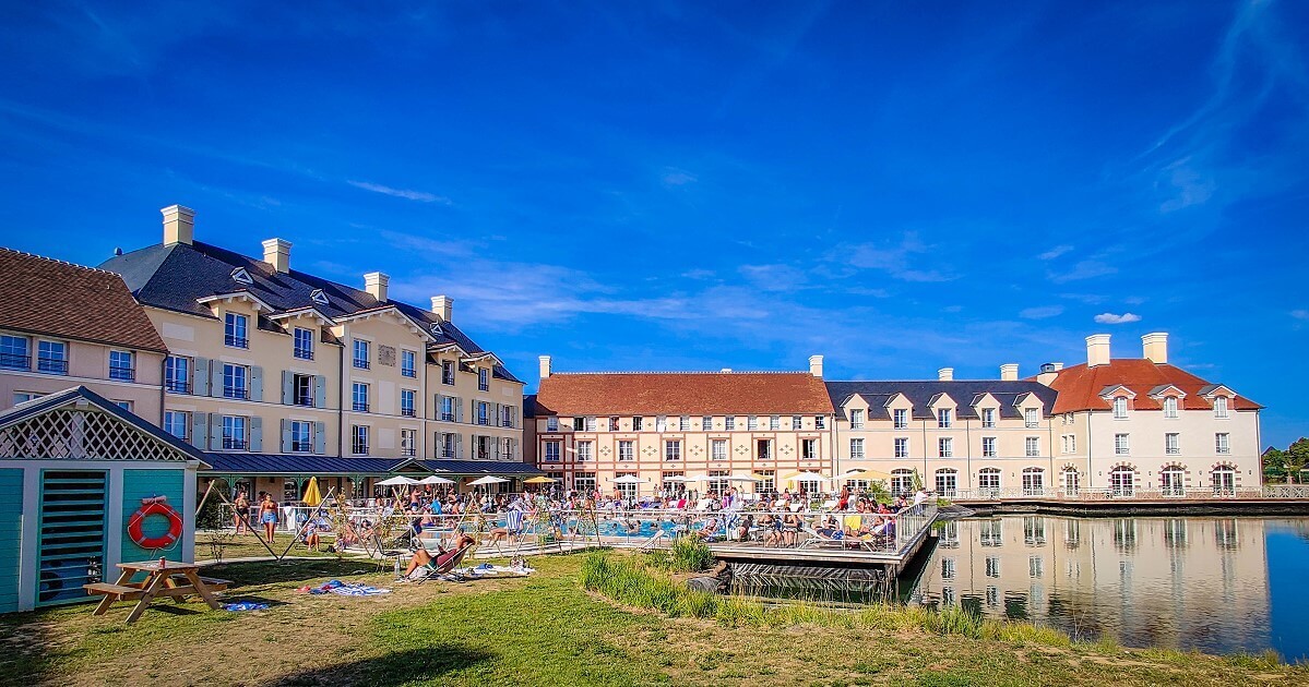 Pool and hotel View of the pool with sun terrace in front of the main building of the Staycity hotel