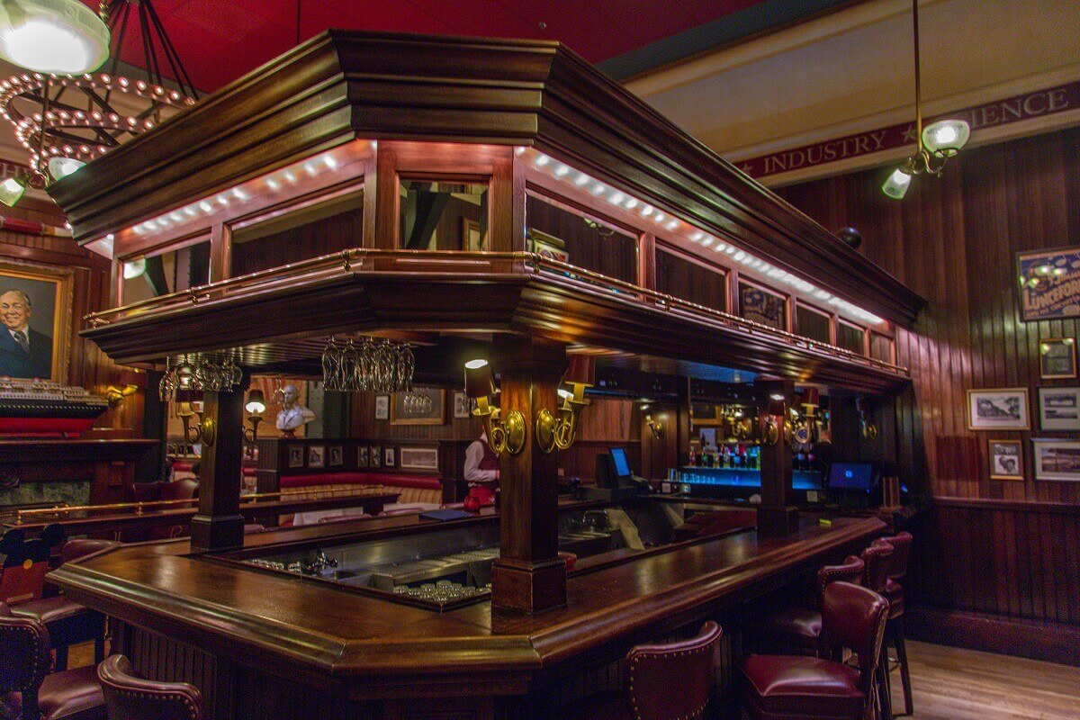 Bar in the entrance area The bar in the entrance area is made of dark wood, all around are heavy stools with wine-red leather covers.