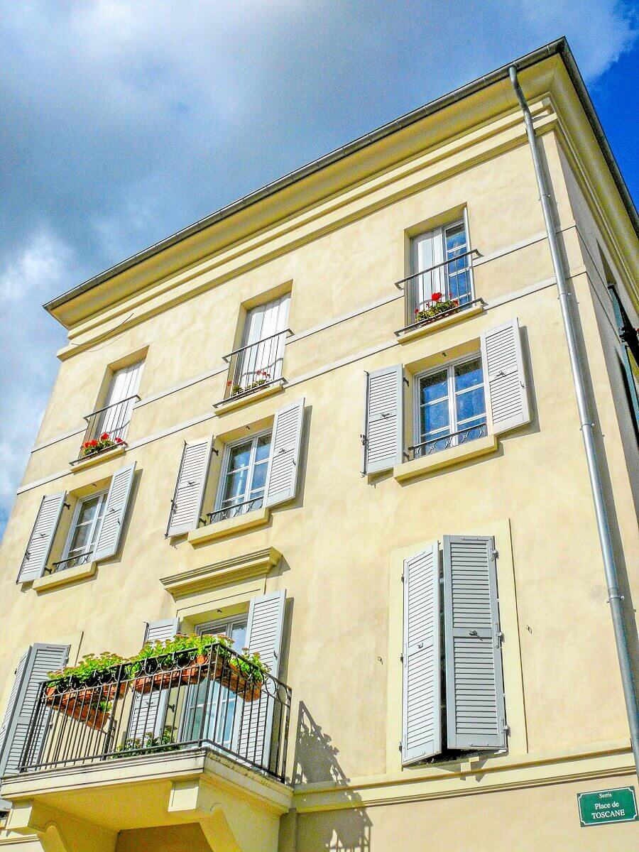 Facade of a building at the Place de Toscane Facade of a building at Place de Toscane, with balcony full of flowers