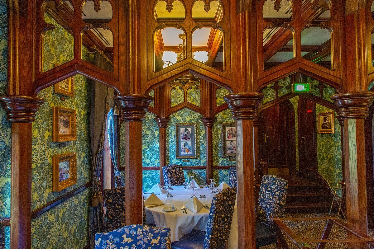 View through wooden arches View through wooden arches to a round table in the Fantasyland room, on the back wall are pictures with scenes from Sleeping Beauty painted by Eyvind Earle